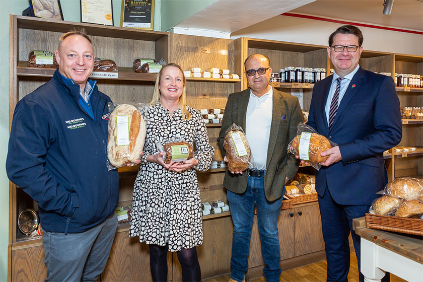 three men and a woman holding loaves of bread